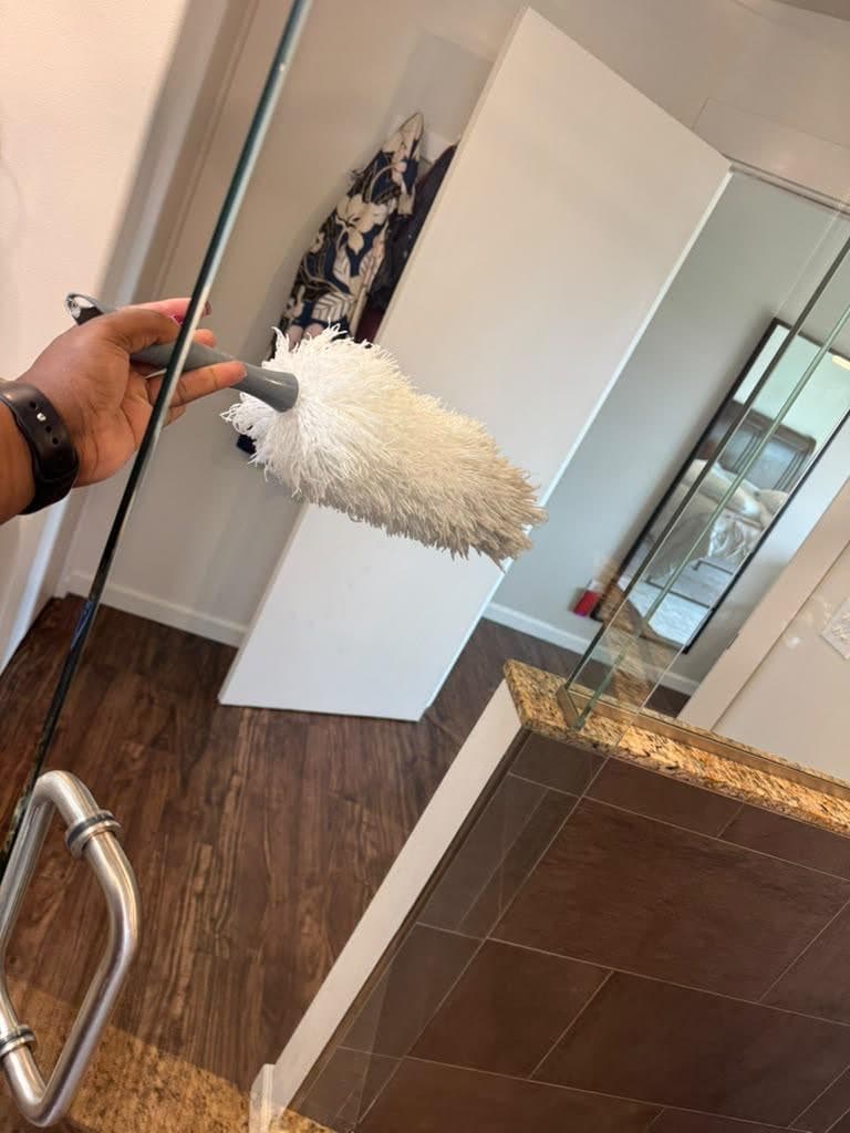 Microfiber duster held up beside a glass shower door