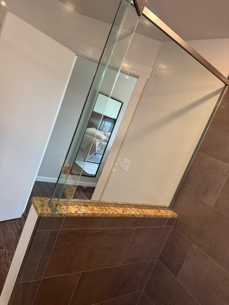 Clean glass shower enclosure with tile walls and a granite ledge