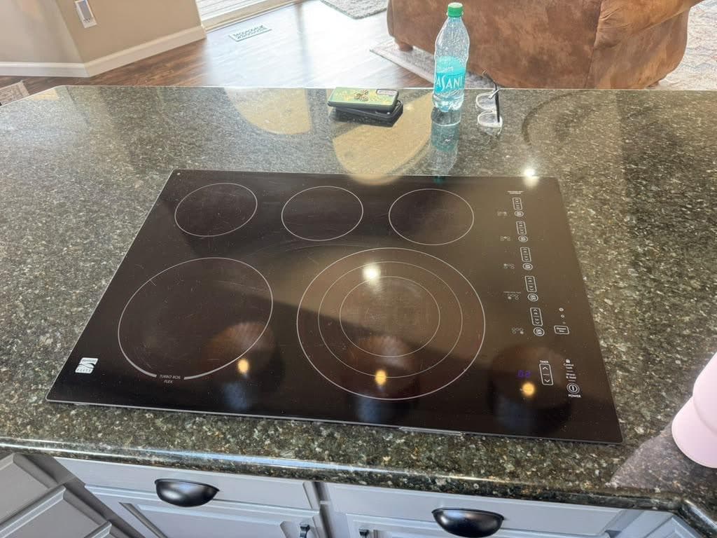 Glass-top electric cooktop set into a granite kitchen island