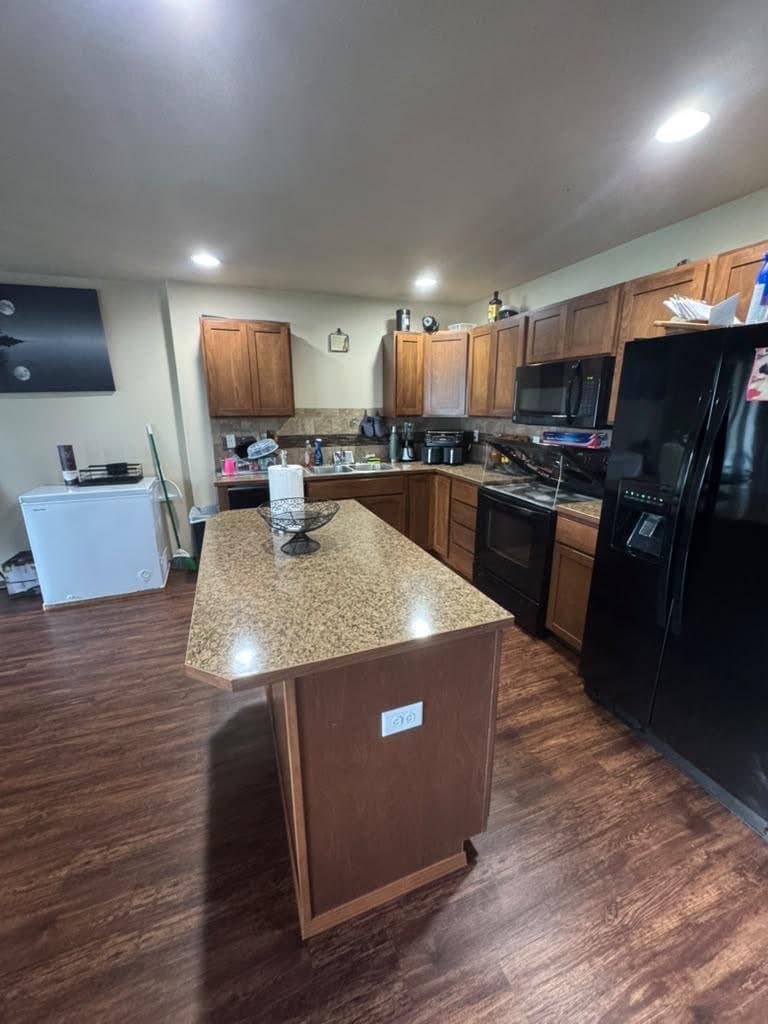 Kitchen with wood cabinets, island and hardwood-look floors ready for a move-out cleaning